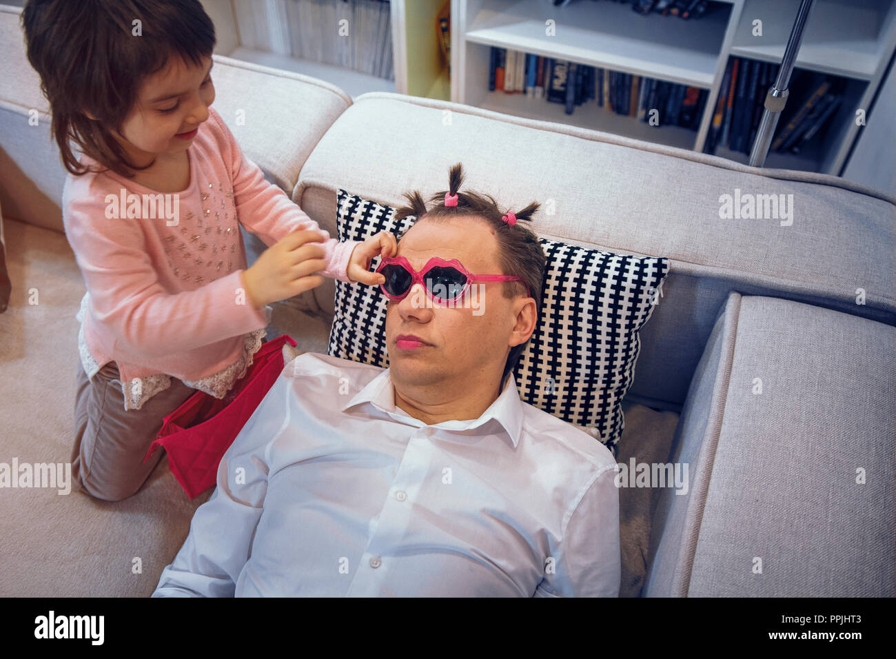 Cute little girl apply lipstick to father while he is sleeping Stock Photo