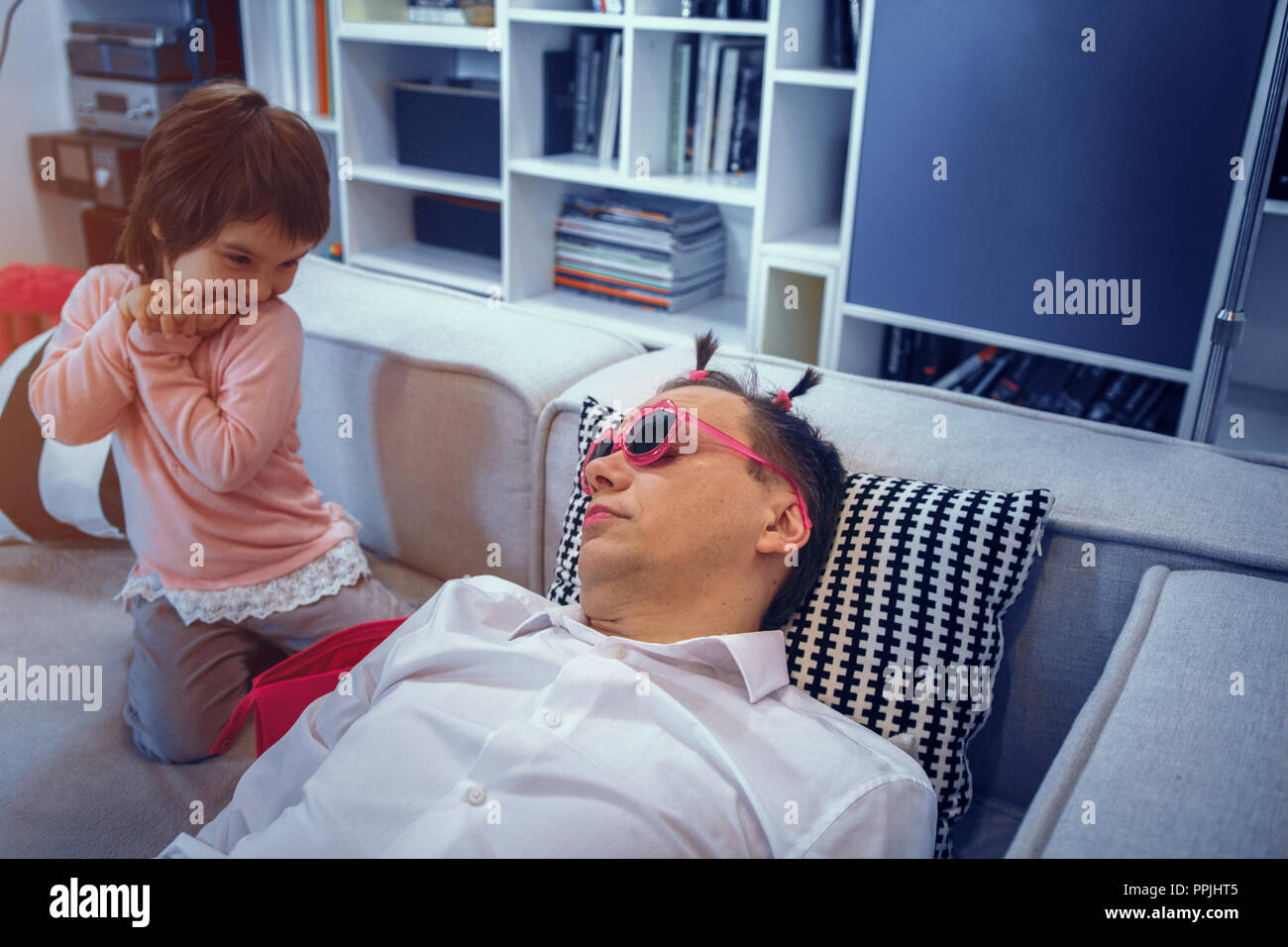 Cute little girl apply lipstick to father while he is sleeping Stock Photo