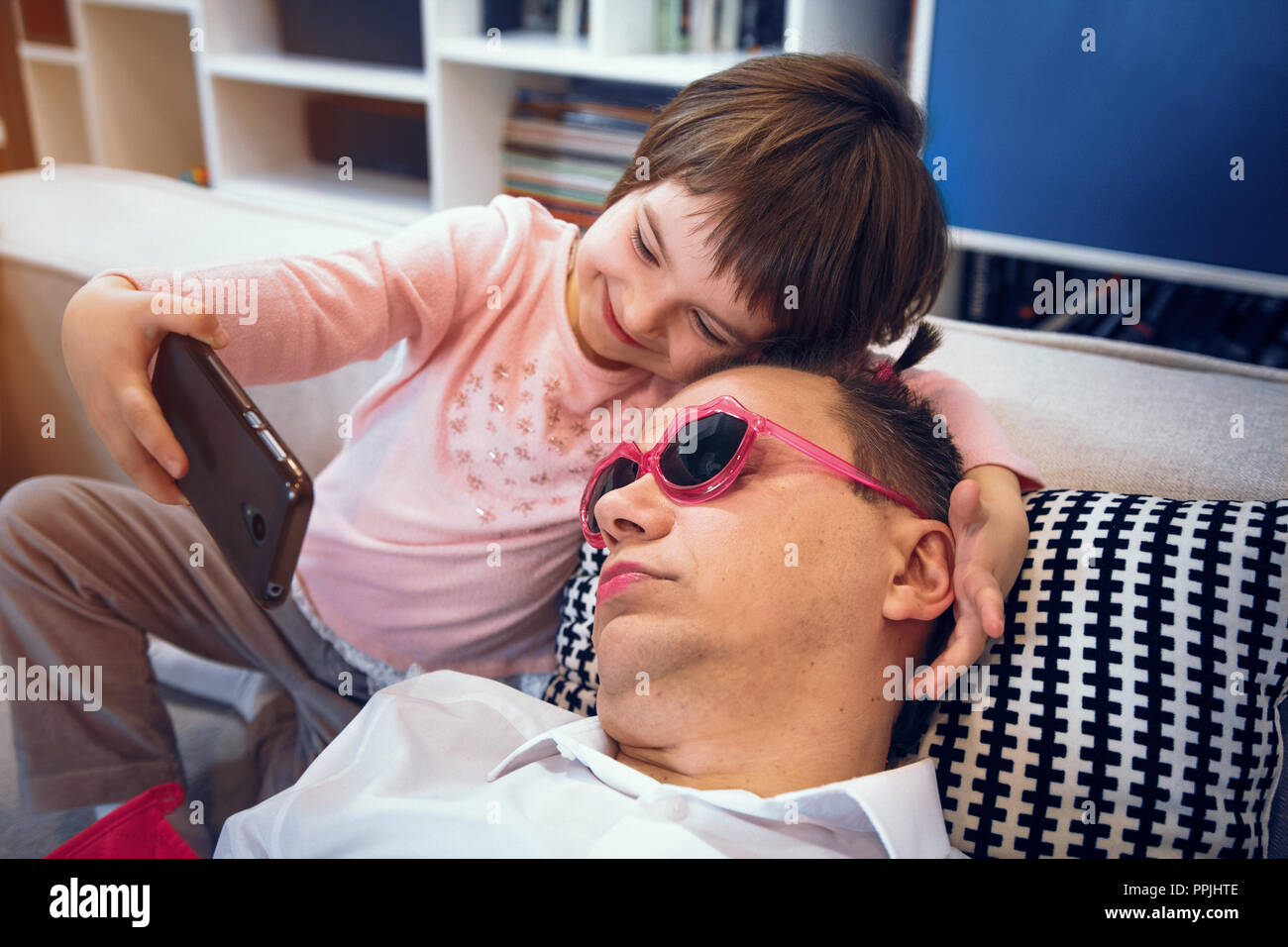 Little girl making selfie with her sleeping father Stock Photo