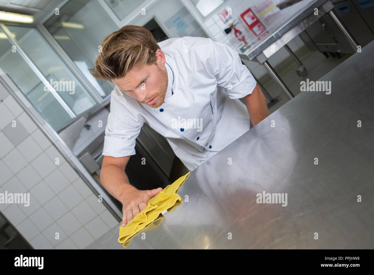 Male Chef Cleaning Stainless Steel Kitchen Work Surface Stock