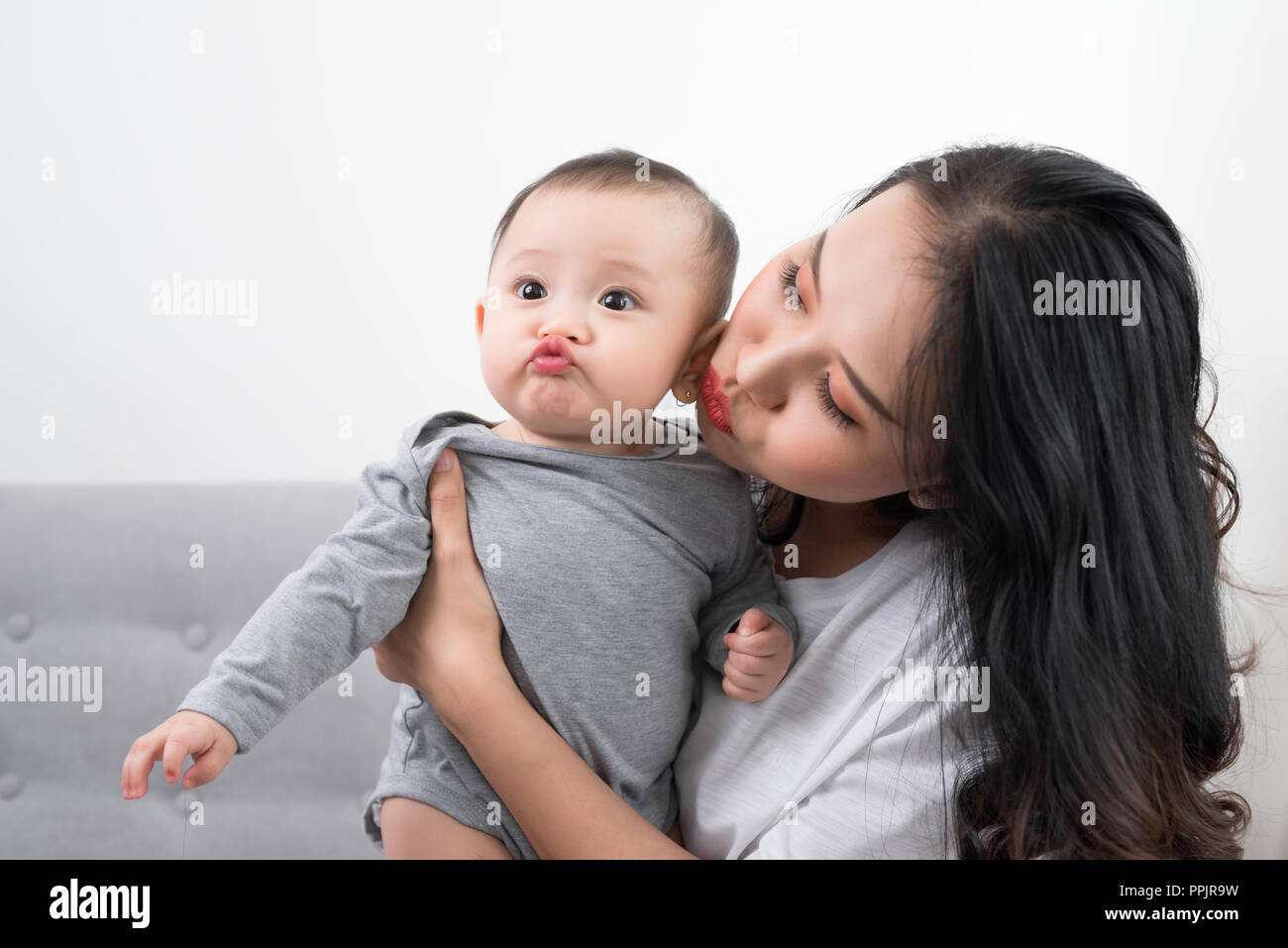 Young mother with her one years old little son dressed in pajamas are relaxing and playing in the living room at the weekend together, lazy morning, w Stock Photo