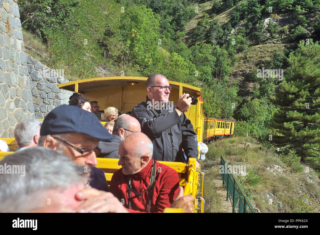 The travelers of the little yellow train of the Pyrenees in the wagon in the open air Stock Photo