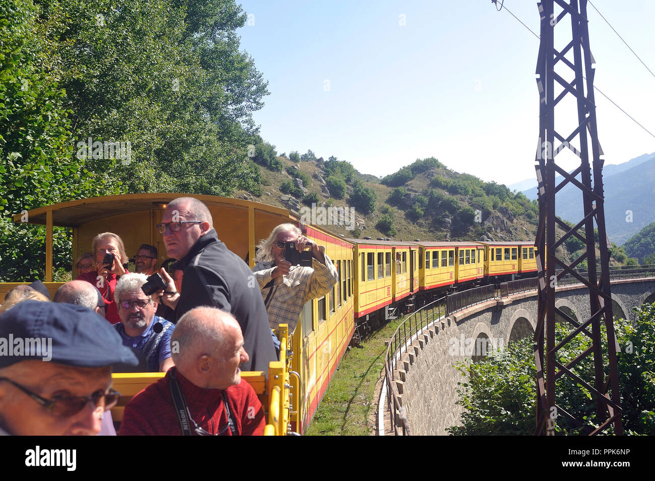 The travelers of the little yellow train of the Pyrenees in the wagon in the open air Stock Photo