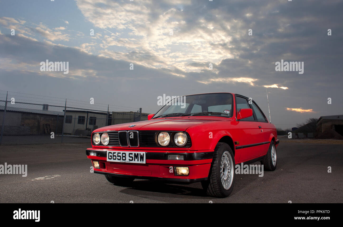 A right hand drive UK spec red 1990 3 door BMW E30 3 Series on an industrial estate in England, UK Stock Photo