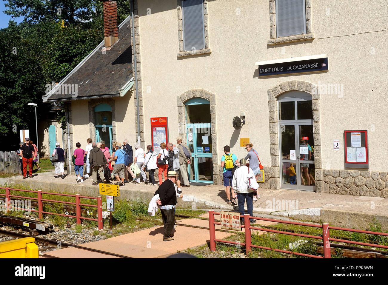 Travelers descend from the Pyrenean yellow train to get out of the Mont Louis train station Stock Photo
