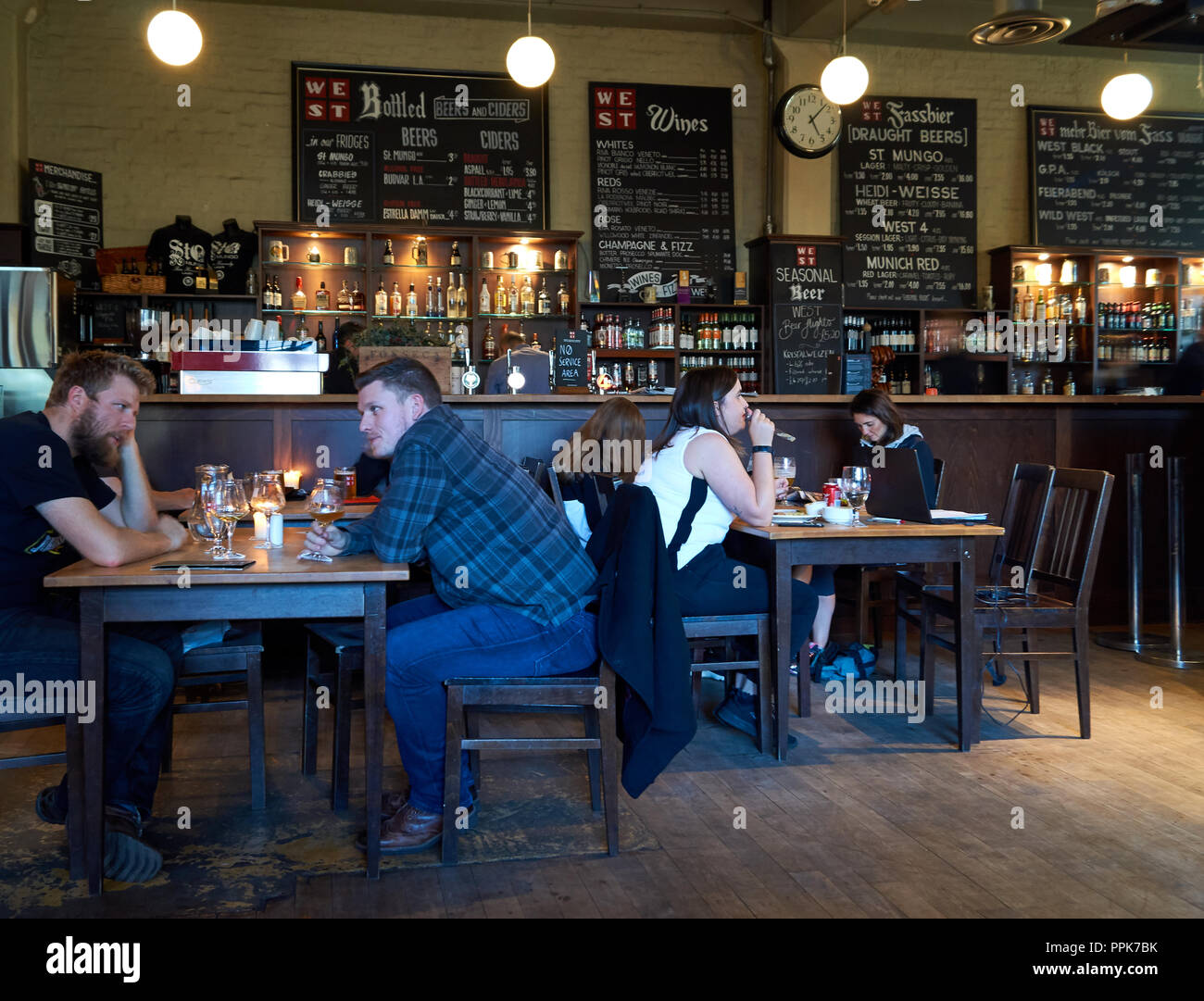 People enjoy a drink inside the popular restaurant and brewery in Glasgow called WEST on the green. Stock Photo