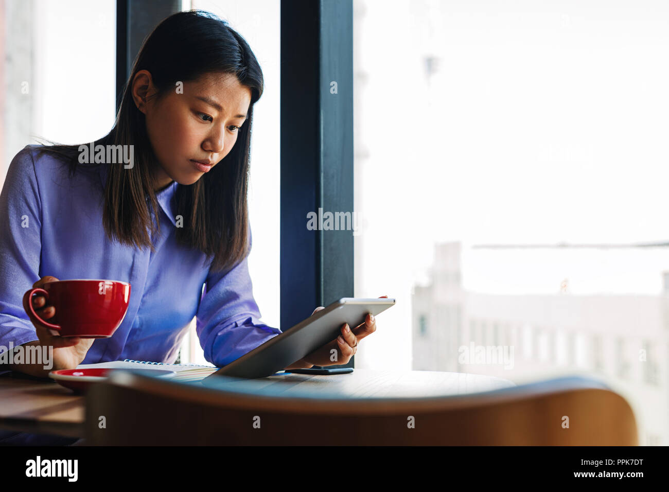 Woman sitting in cafe and using tablet pc Stock Photo