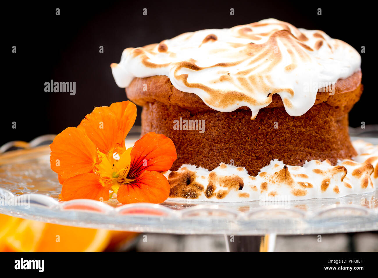 Whole Orange cake with meringue topping and edible flowers Stock Photo