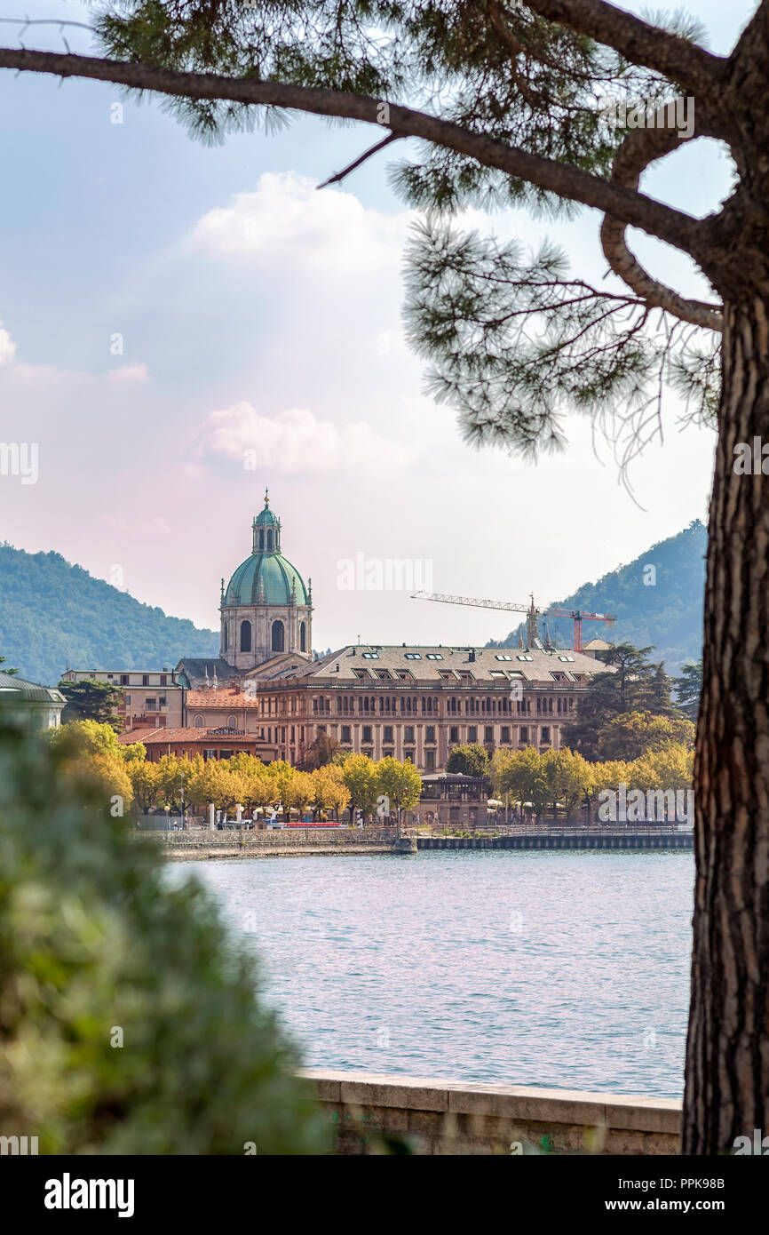 The Cathedral of Como and its dome framed between the lake and pine trees, Lombardy, Italy Stock Photo