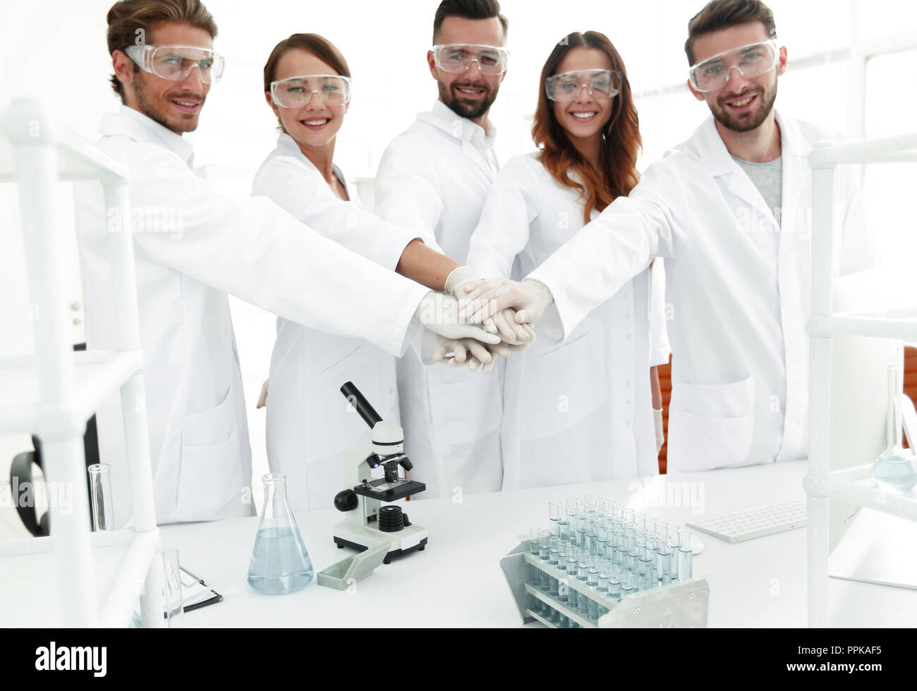 successful team of young scientists with hands clasped together Stock ...