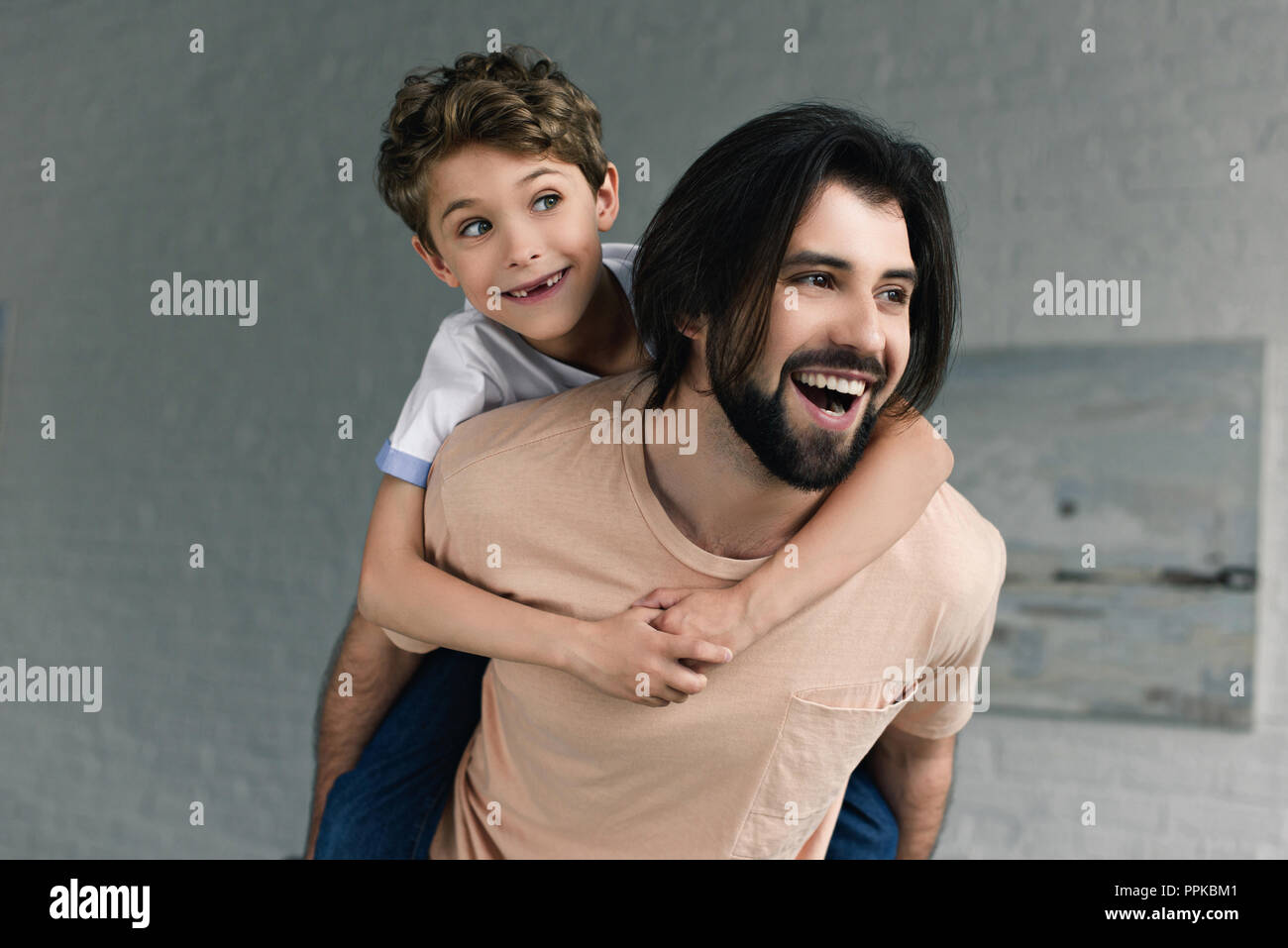 portrait of happy father and little son piggybacking together at home Stock Photo