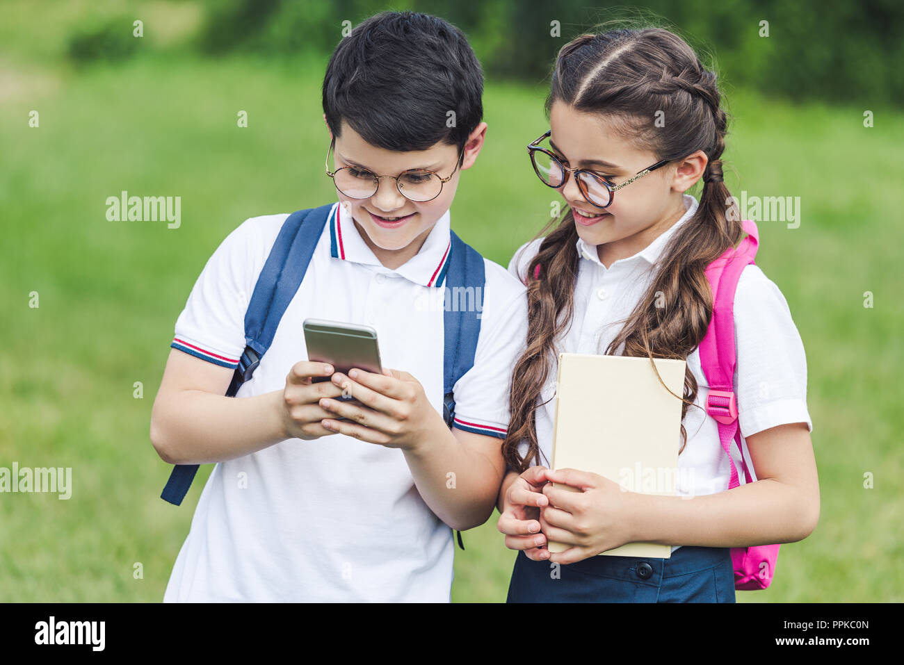 happy schoolchildren using smartphone outdoors together Stock Photo