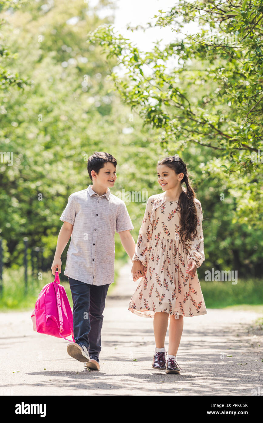 happy kids holding hands and walking by park Stock Photo - Alamy