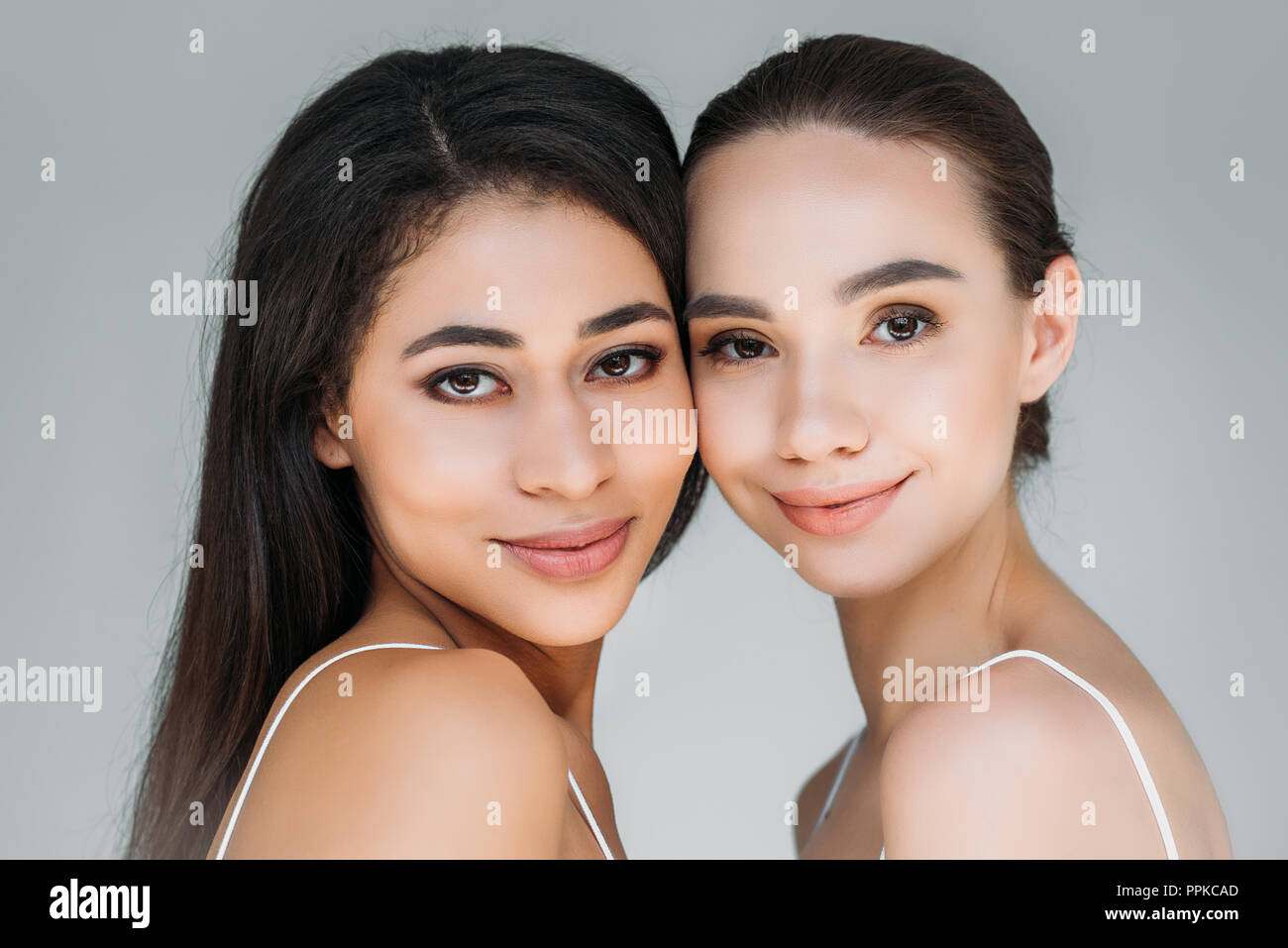 portrait of smiling multicultural women looking at camera isolated on ...