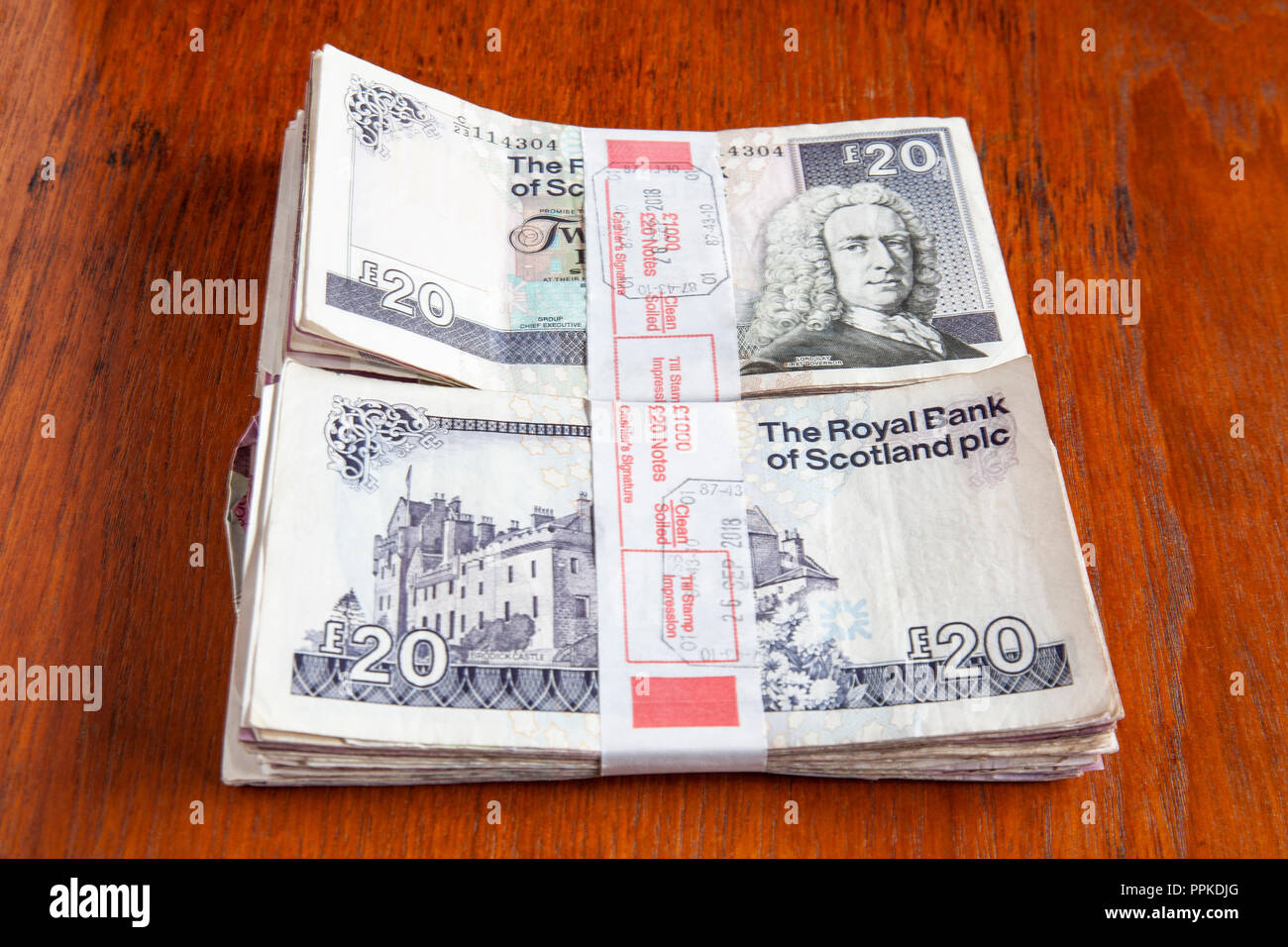 Money left on the table. Two bundles of £1000 each in used Scottish £20 banknotes from the Royal Bank of Scotland and the Clydesdale bank. Stock Photo