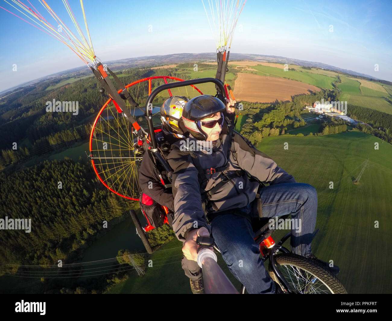 Powered paragliding tandem flight, man taking selfie with action camera