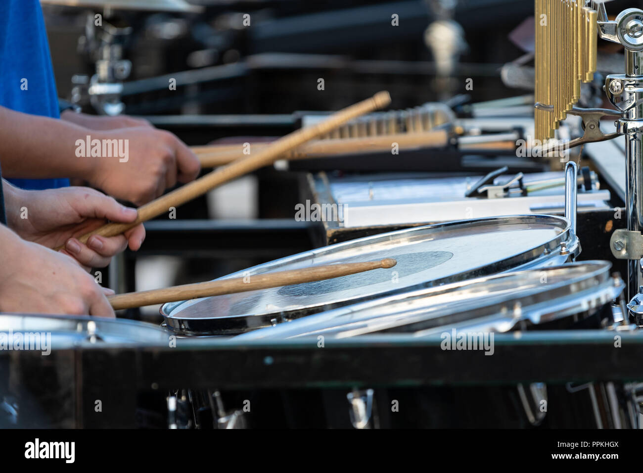 the flashing drumsticks of a sideline percussionist at marching band rehearsal Stock Photo
