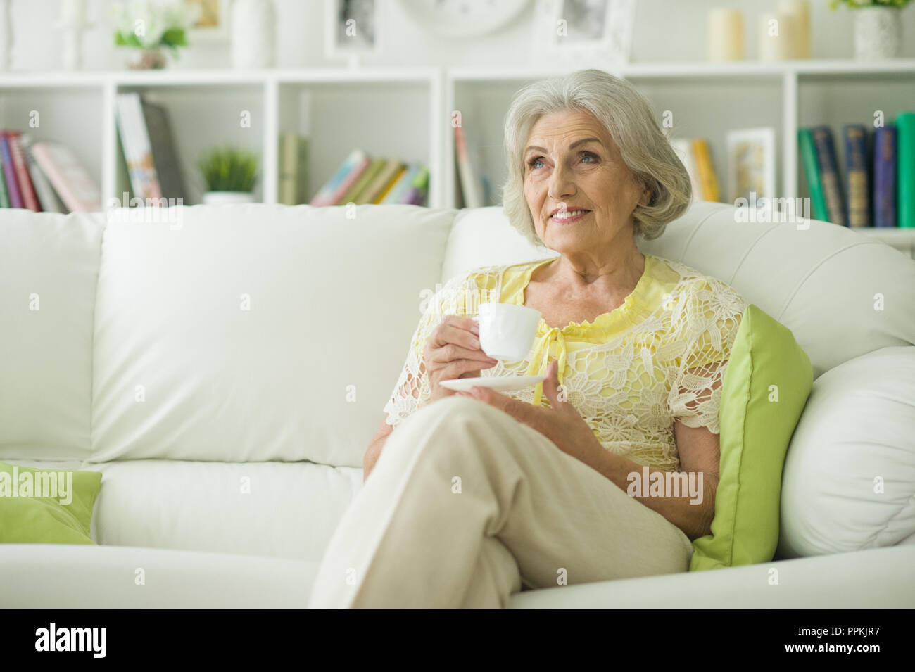 Portrait of beautiful senior woman sitting on sofa Stock Photo - Alamy