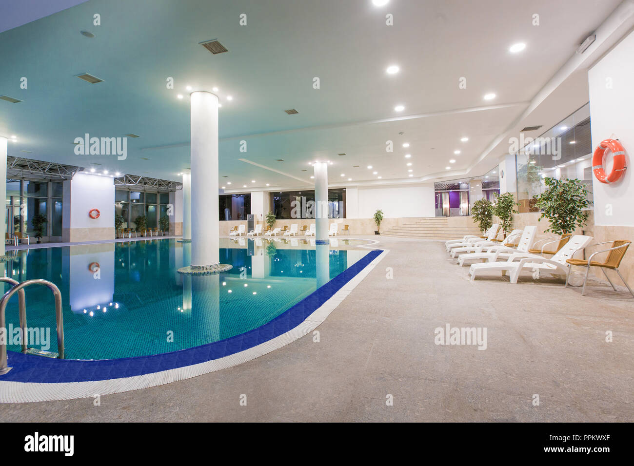 Indoor pool in hotel, sun loungers and orange life ring weighs on the wall  Stock Photo - Alamy