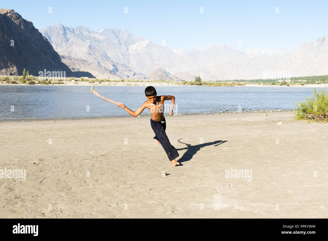 Pakistani kids play hockey on sand, Skardu, Gilgit-Baltistan, Pakistan Stock Photo