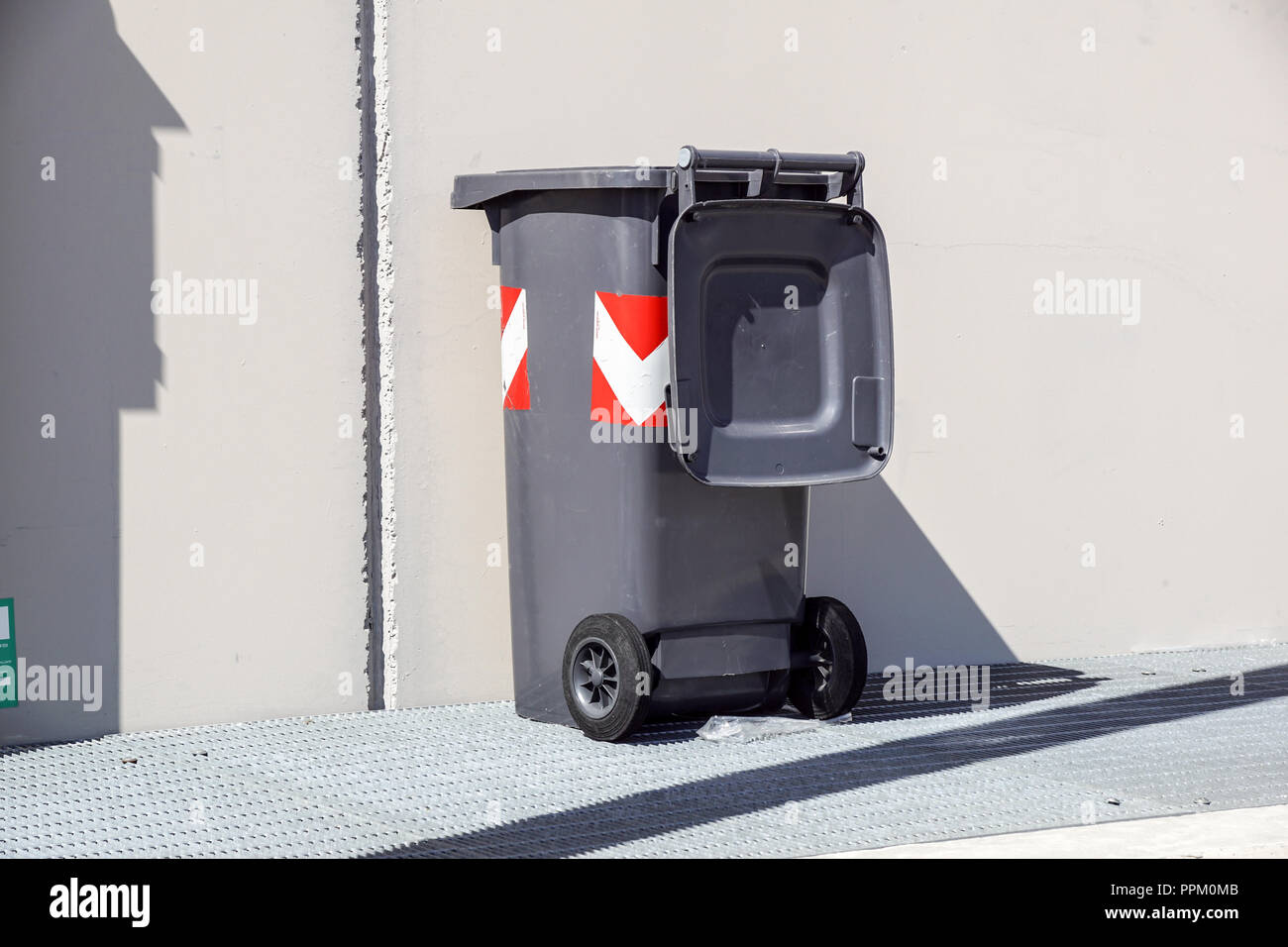 The photo shows old green bin with full garbages. It is a stinking bin