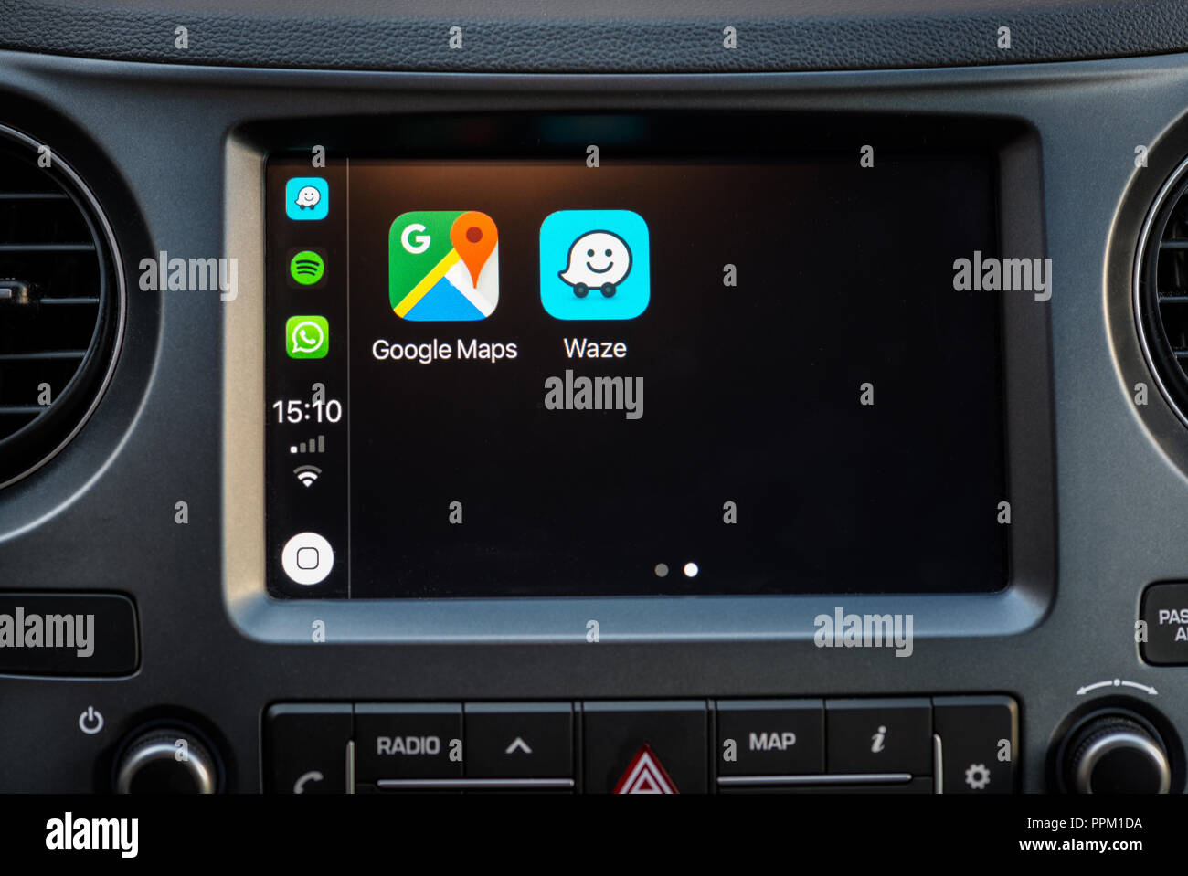 Apple Carplay screen in car dashboard displaying Google Maps and Waze apps Stock Photo