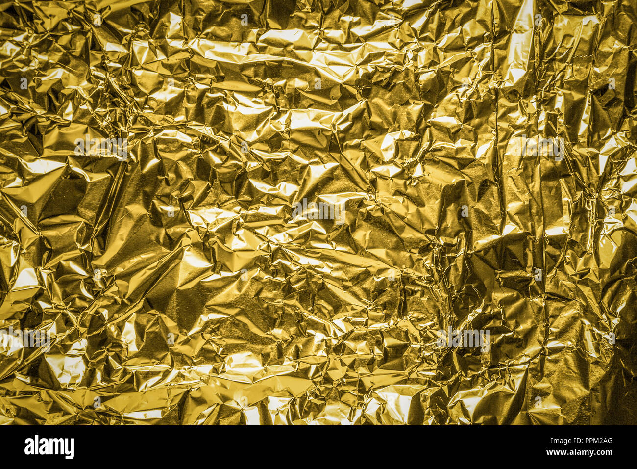 The close up of a golden surface aluminum foil background texture. Gold, metallic background. Stock Photo