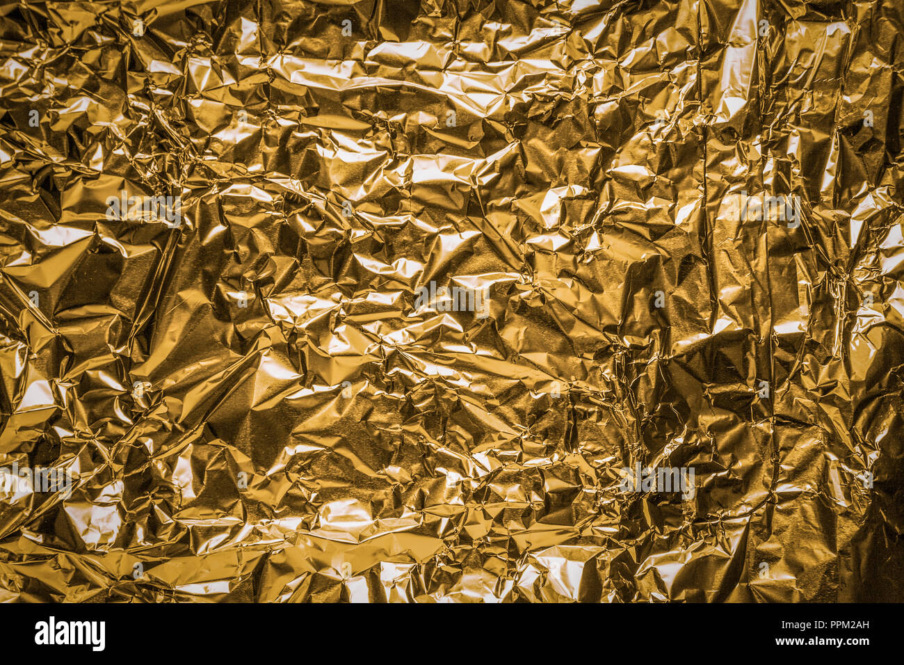 The close up of a coppery surface of aluminum foil. Metallic background. Stock Photo