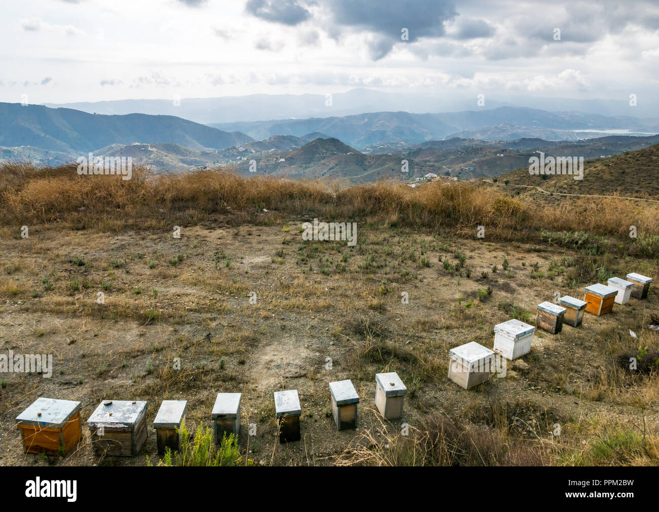 Row of beehives on hilltop overlooking valleys and mountains, Axarquia, Andalusia, Spain Stock Photo
