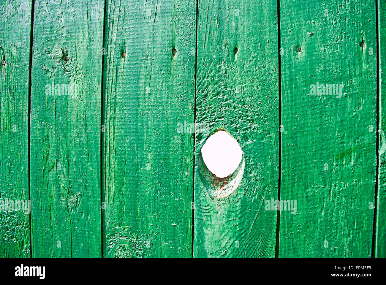 hole in a green wooden fence Stock Photo Alamy