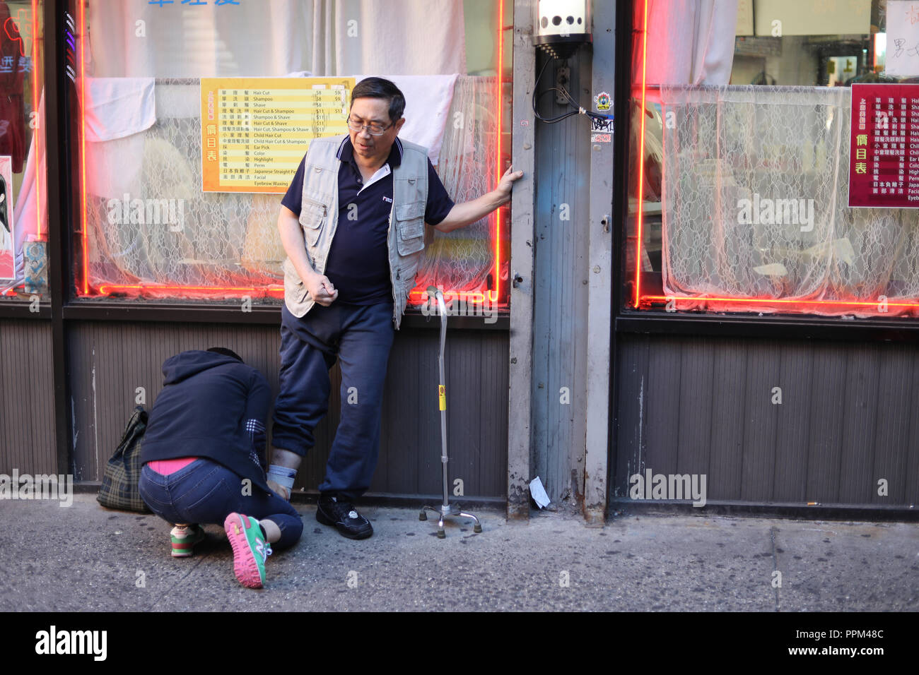 Chinatown, New York - February 10, 2016: Unidentified person helping an unidentified handicaped man in Manhattan, New York City Stock Photo