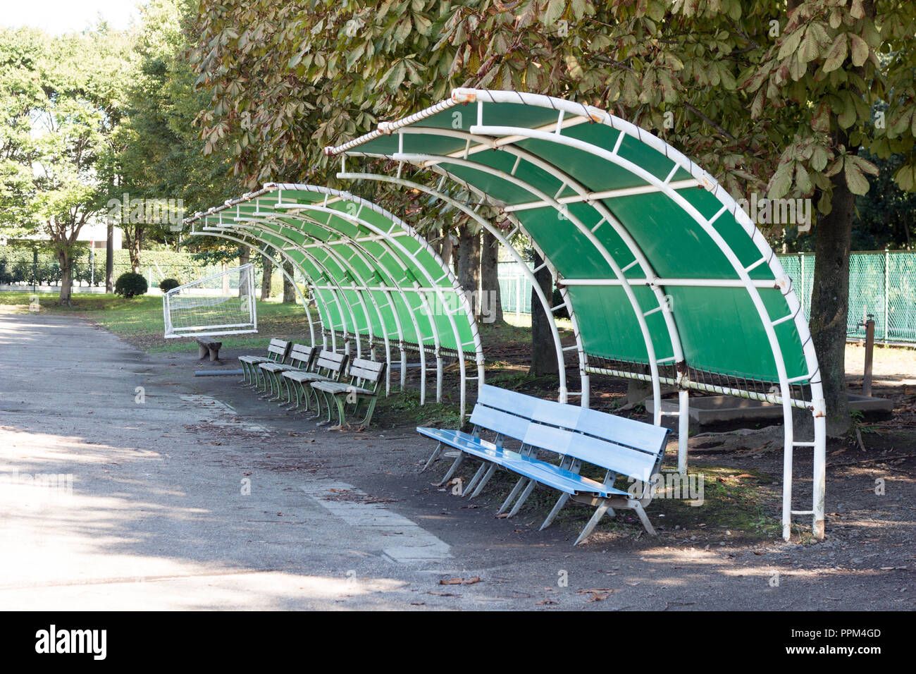 Blue plastic bench with retro vinyl green roof in park in early autumn Stock Photo