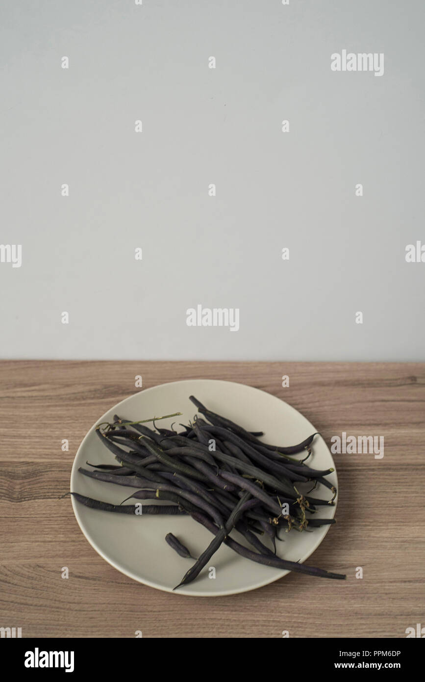 Top View of Uncommon Purple Green Bean Pods on a Plate Stock Photo
