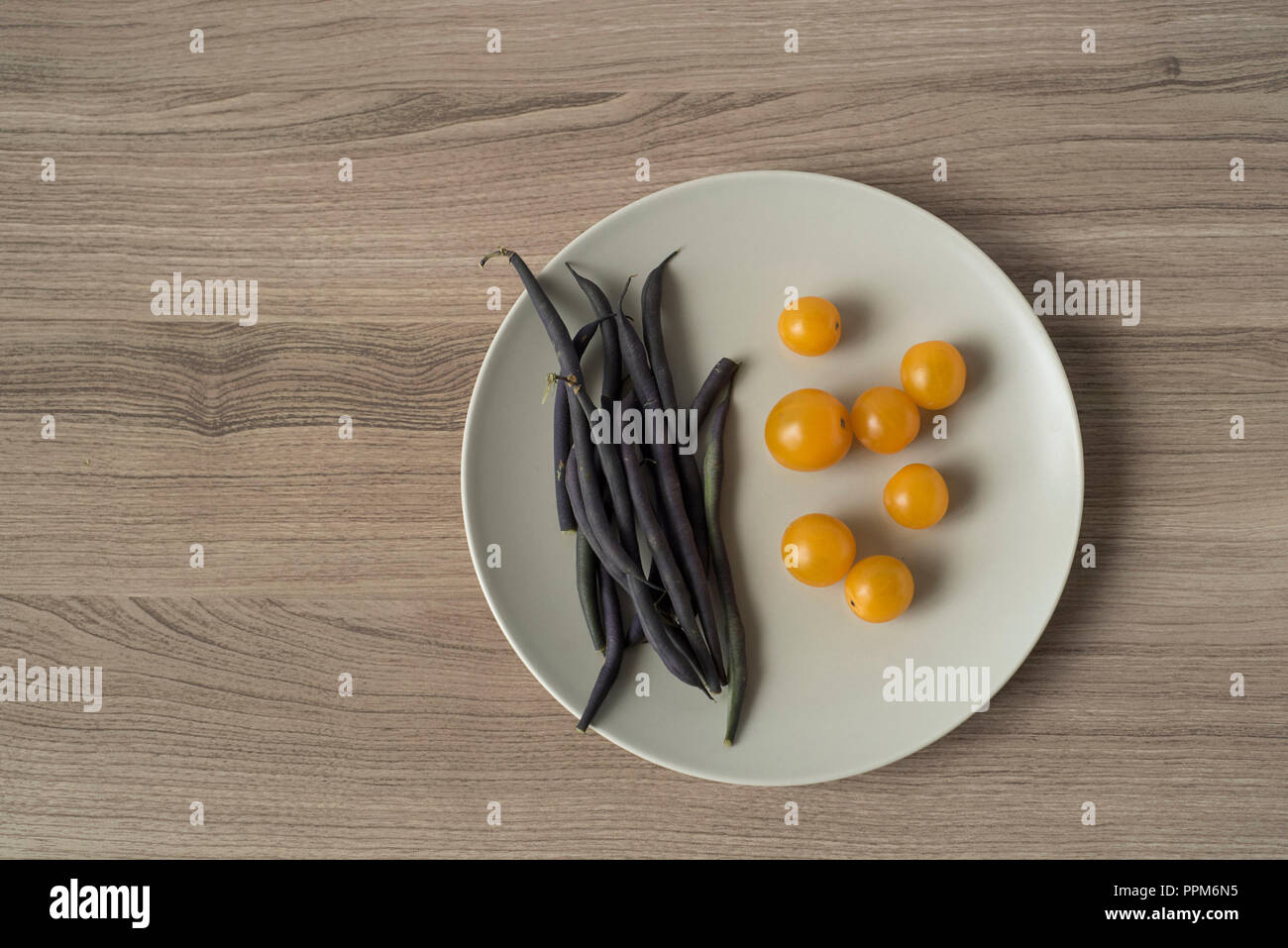 Veggies on a Plate Horizontal Overhead Including Purple Beans and Yellow Tomatoes Stock Photo
