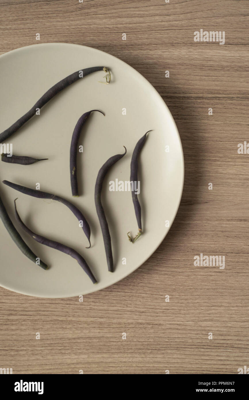 Purple Green Beans Scattered on a Plate Vertical Overhead View Stock Photo