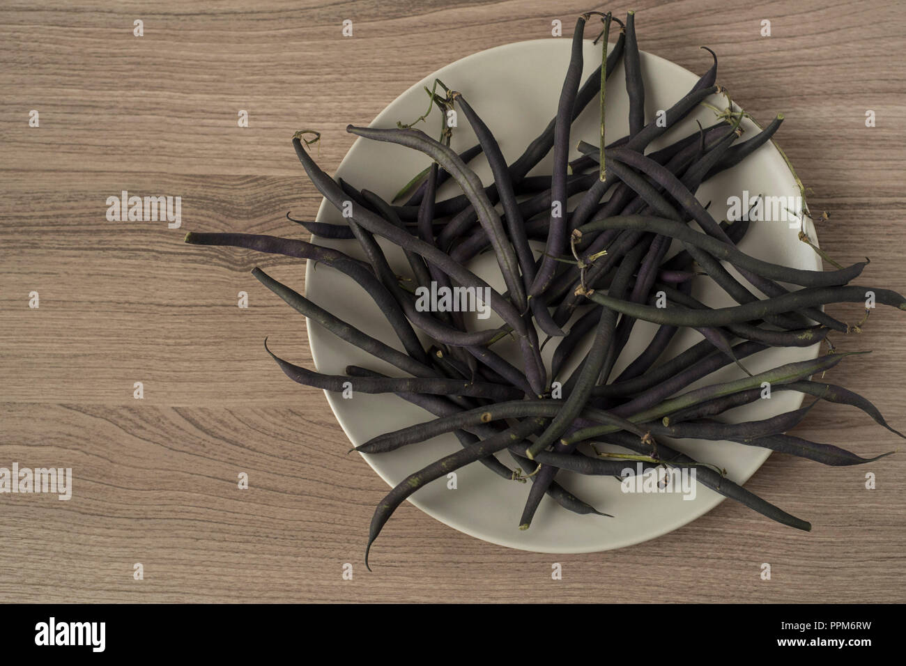 A Tangle of Purple Beans Overwhelms a Plate Stock Photo