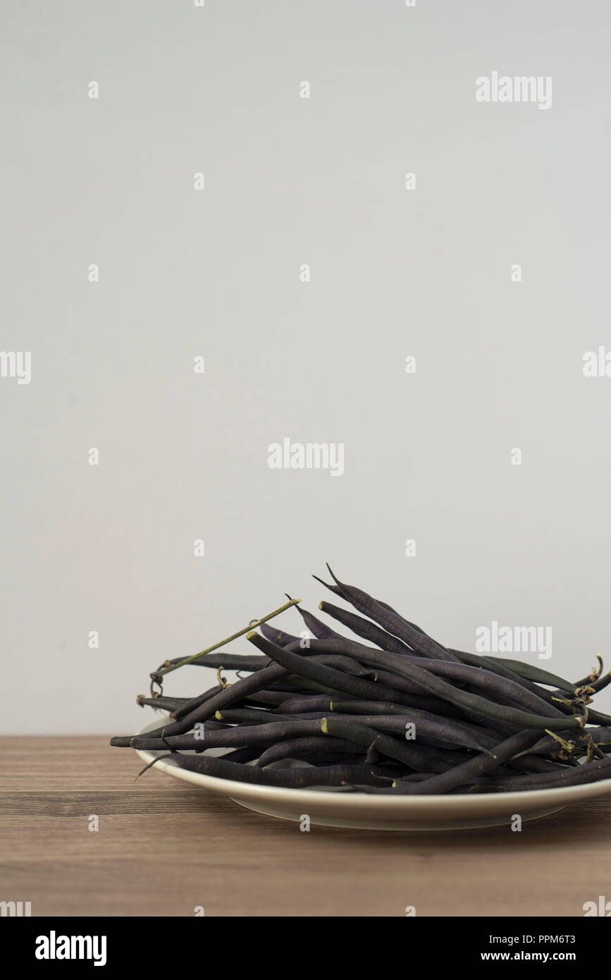 A big pile of purple green beans on a plate ready to eat Stock Photo