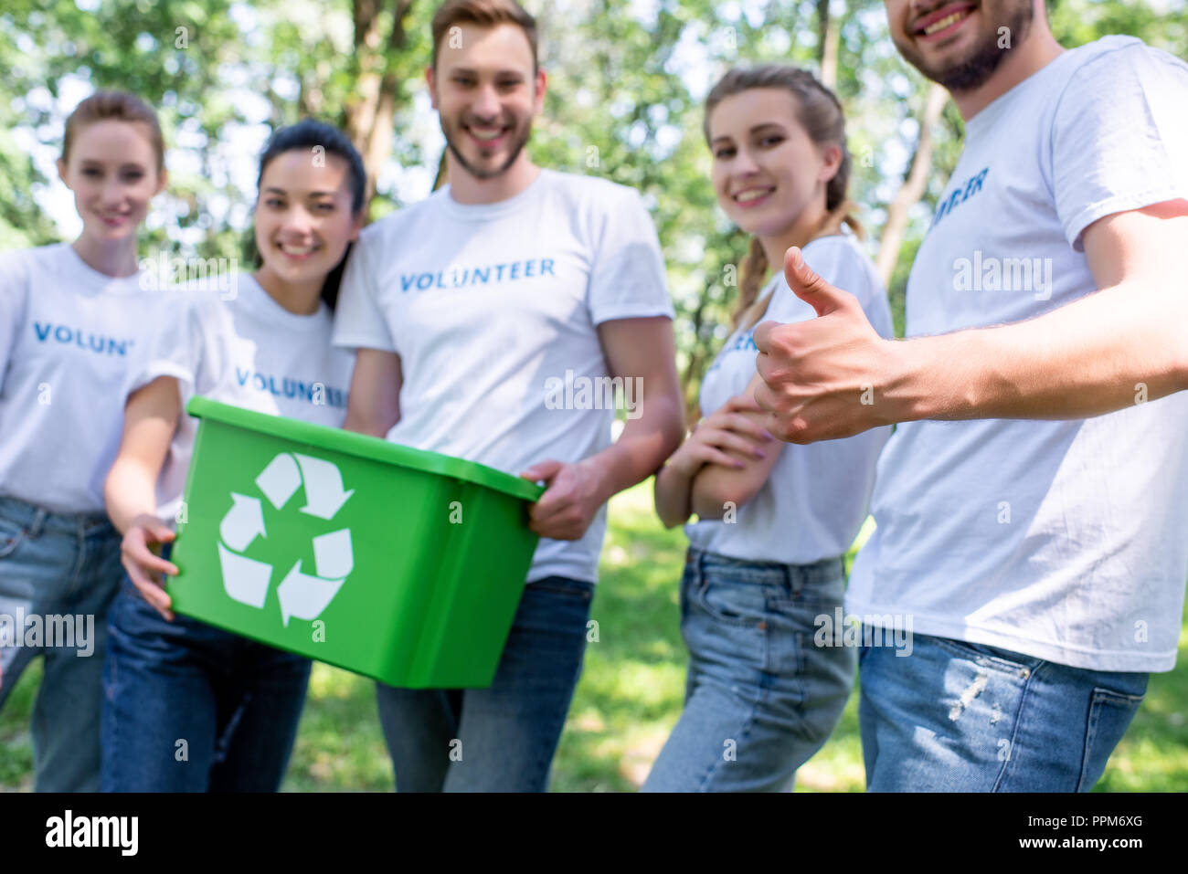 volunteers with green recycling box showing thumb up after cleaning