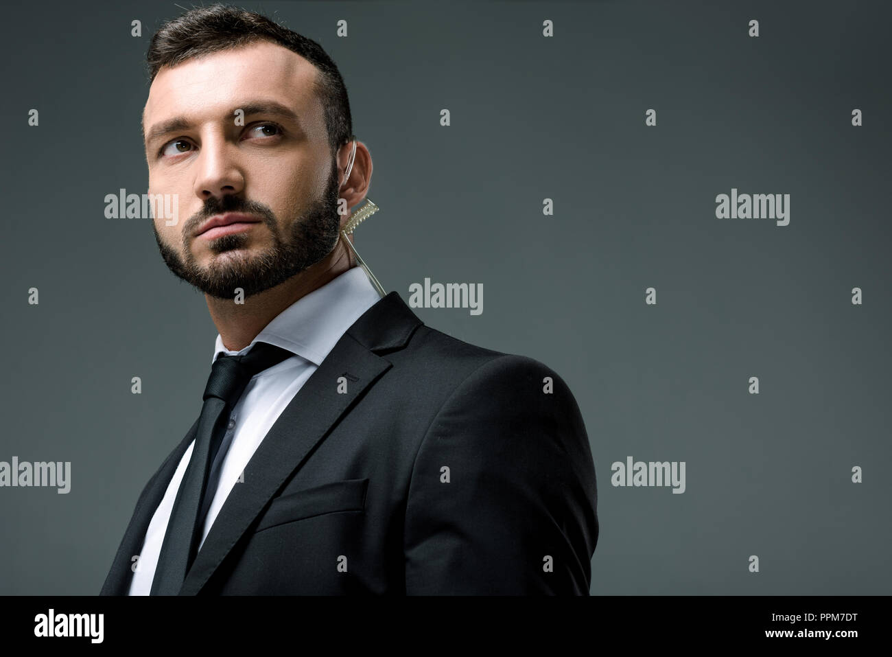 handsome security guard with security earpiece looking away isolated on grey Stock Photo