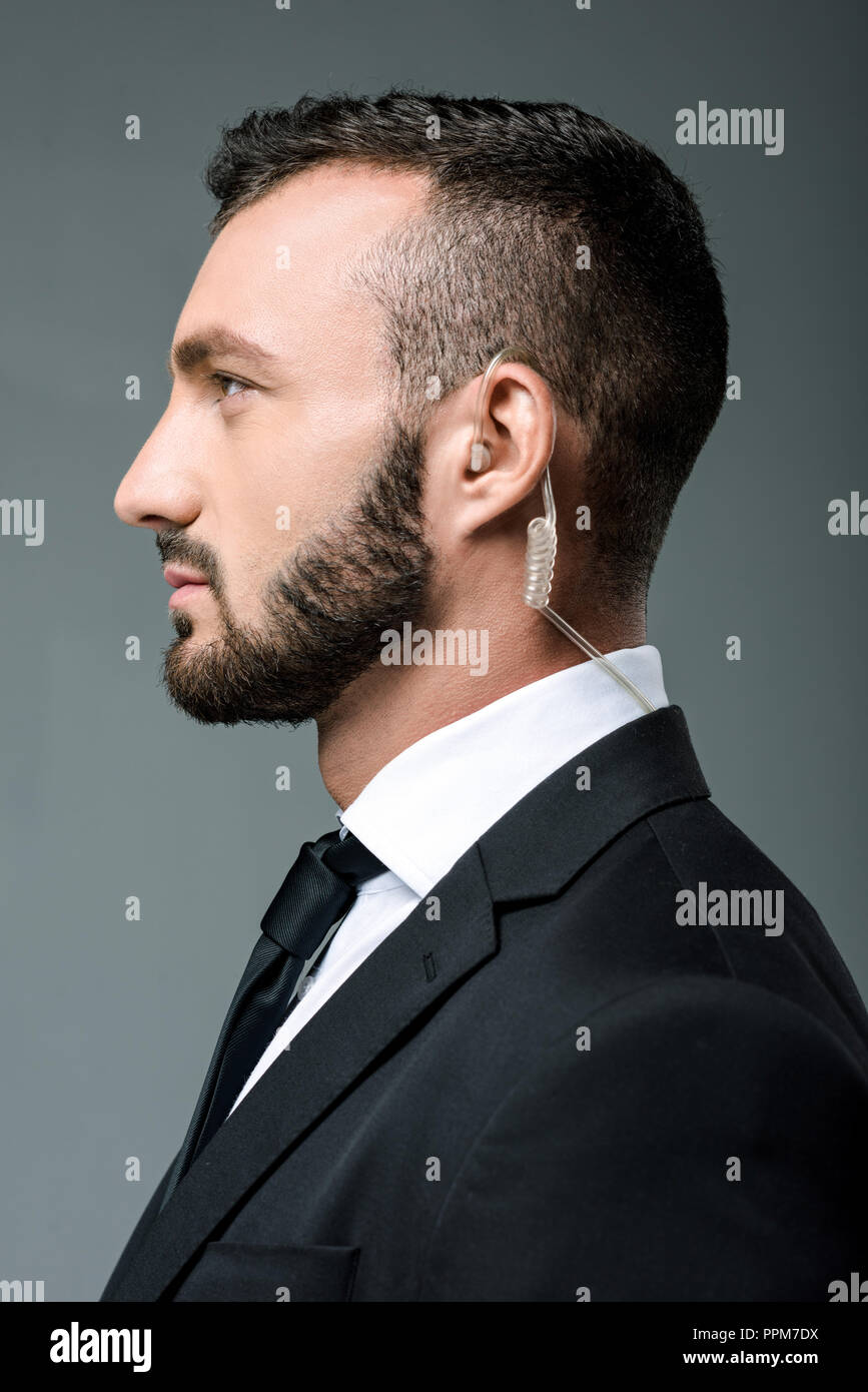 profile of handsome security guard with security earpiece isolated on grey Stock Photo