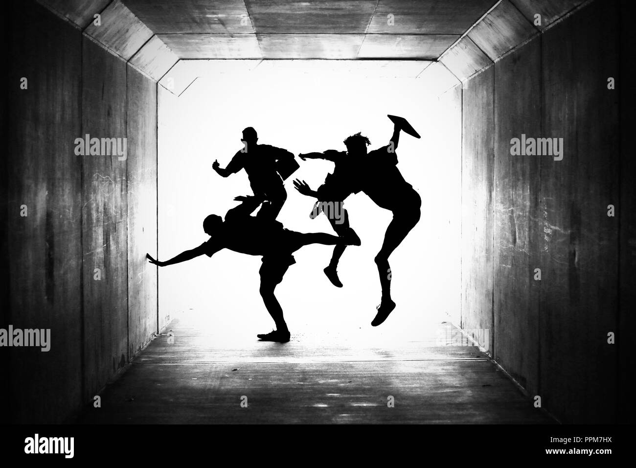 creative concept for graduation, leaving school, finished schooling or holidays. group of silhouetted boys jumping in the air in a tunnel. friends Stock Photo