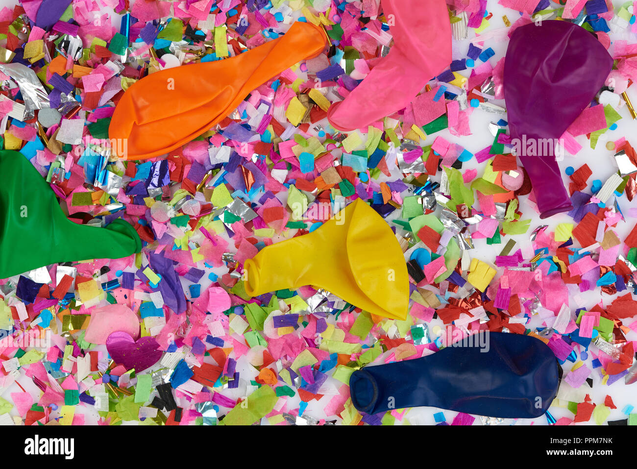 Finished party theme. Empty  balloons lay on colorful confetti background Stock Photo