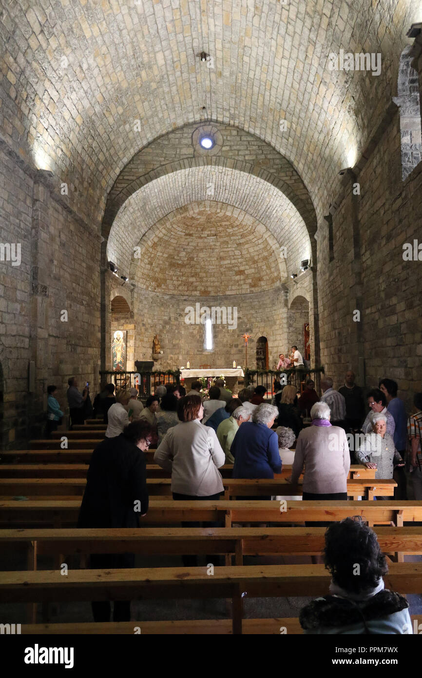 The internals and the altar of the stone romaneque Holy Mary Church (Iglesia de Santa Maria) during the celebration of a mass in Ainsa, Spain Stock Photo
