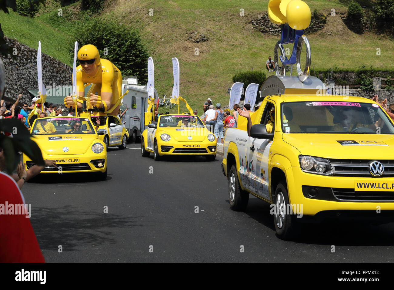 The yellow Le Crédit Lyonnais cars throwing free gifts during the 2018 Tour de France 17th stage in Soulan, French Pyrennìees, ans supporters. Stock Photo