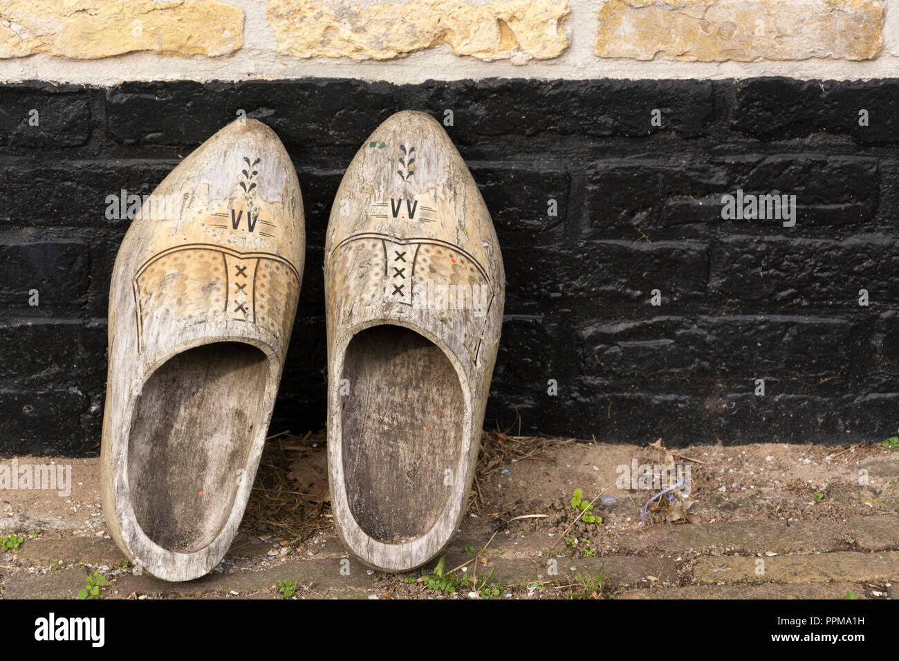 View on a pair of traditional vintage retro Dutch old decorated wooden  shoes, put against the wall before entering the house Stock Photo - Alamy