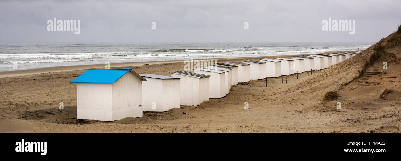 View on the beach huts on the west coast area of Texel. Panoramic view on the North Sea on a day in autumn with beautiful waves and a heavy grey sky. Stock Photo