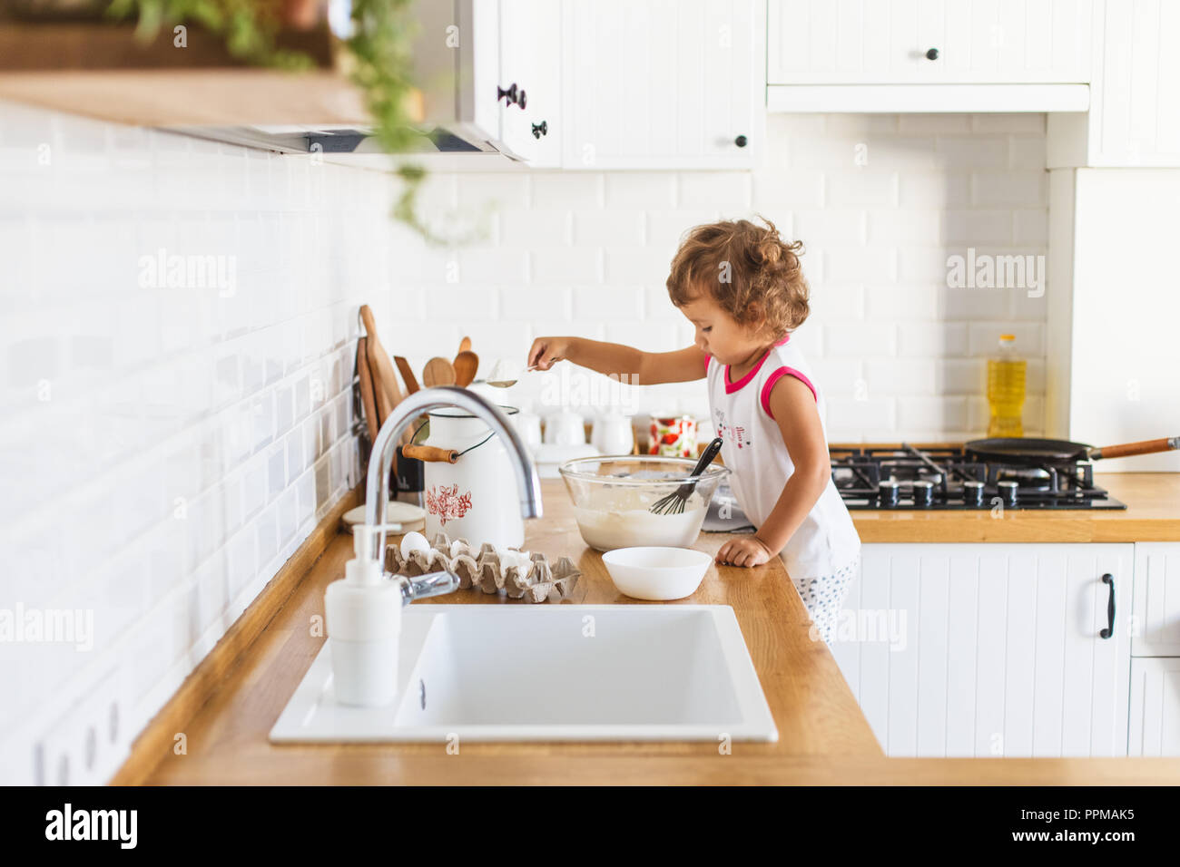 Little Girl Preparing Dough For Pancakes At The Kitchen Concept
