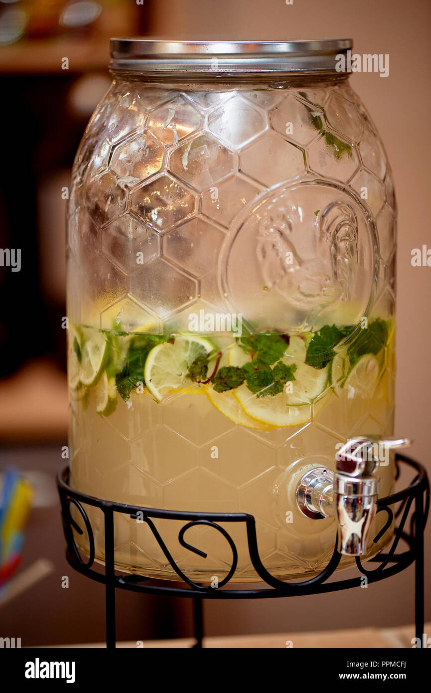 Lemonade in a big jar with a tap.Oranges and lemon. Refreshing summer