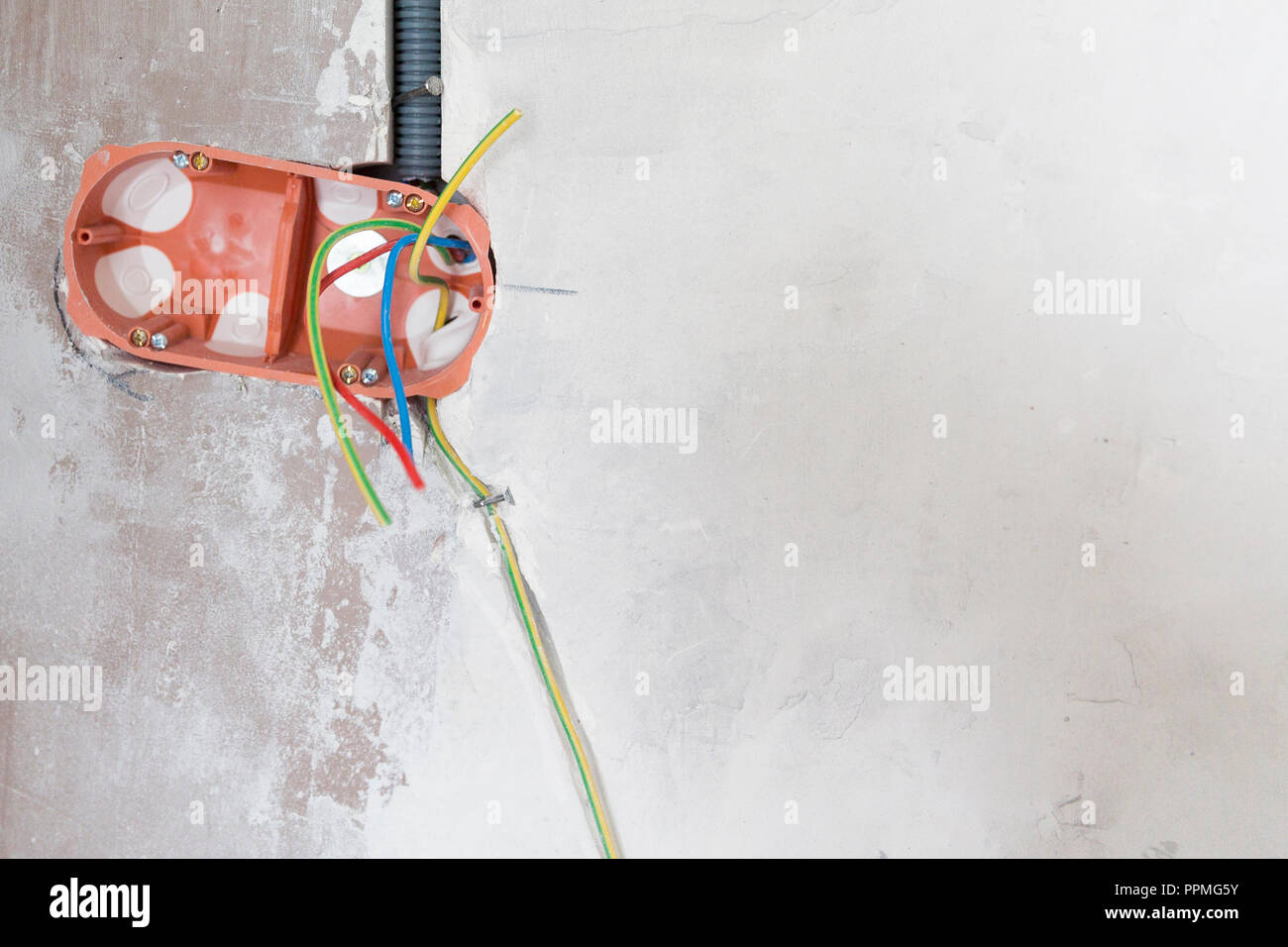 Electrical renovation work wiring in pipe white plaster wall Stock