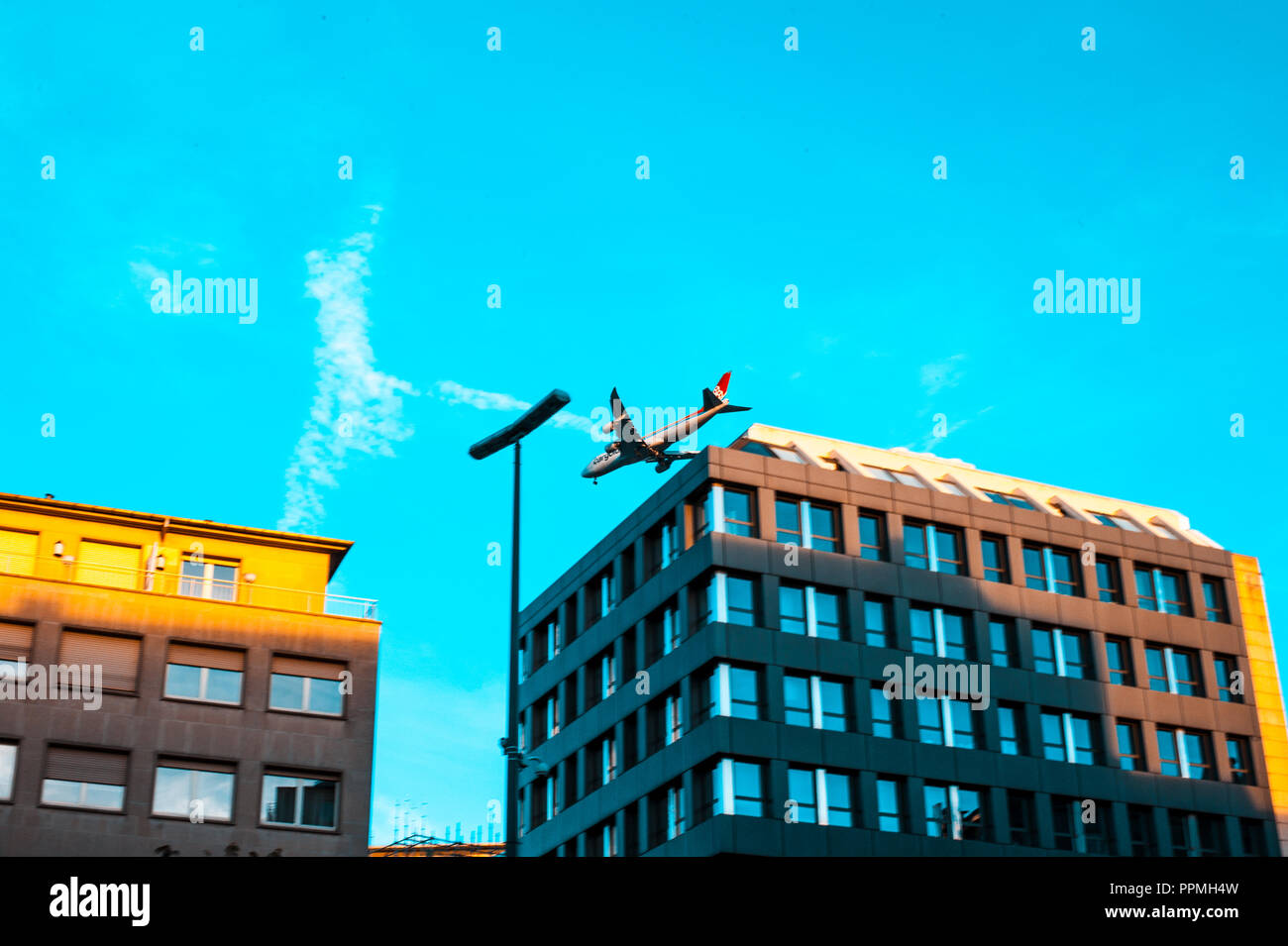 Airplane passing through buildings, Luxembourg Stock Photo